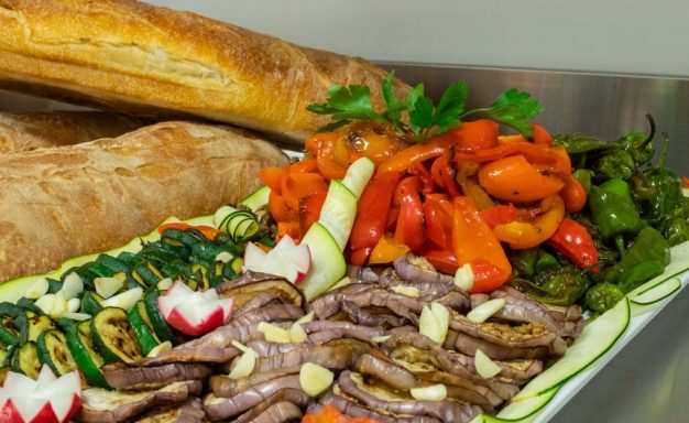 Ein platter mit Fleisch, mariniertem Gemüse und frischem Brot.