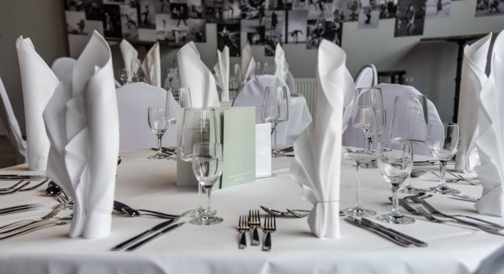 Elegantly gedeckter Tisch mit weißen Servietten und Gläsern für eine festliche Veranstaltung.