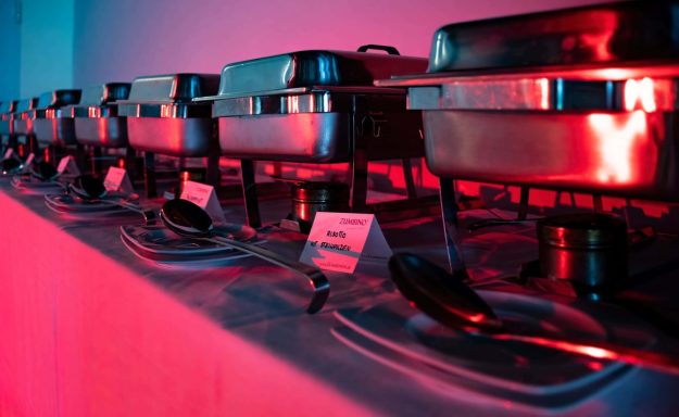 Buffet mit mehreren Warmhaltebehältern in rotem Licht.